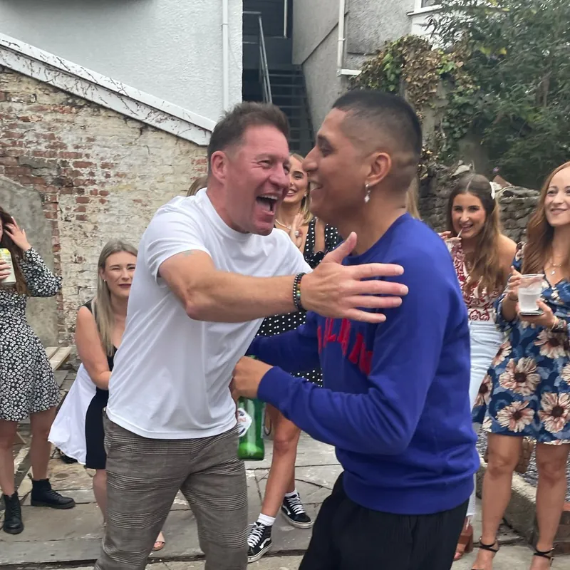 Ryan, in a blue jumper, dancing with a man in a white T-shirt at an outdoor party